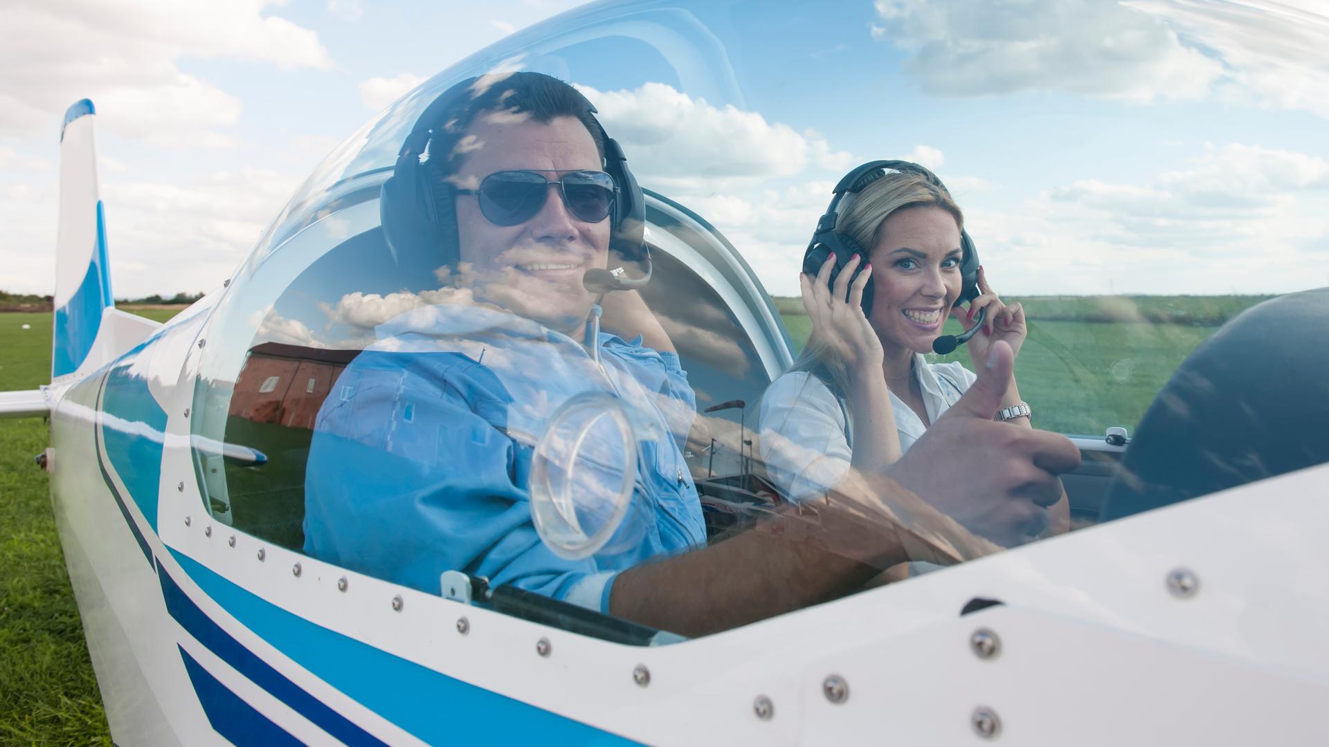 A smiling couple sits inside an airplane before takeoff